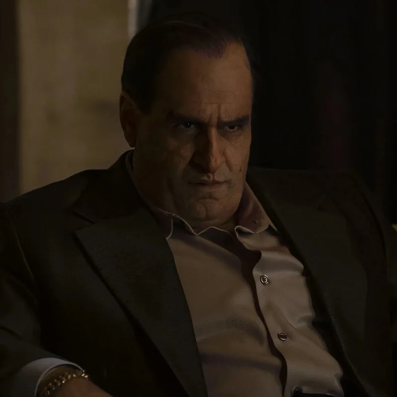 Oz Cobb, sentado, con traje oscuro